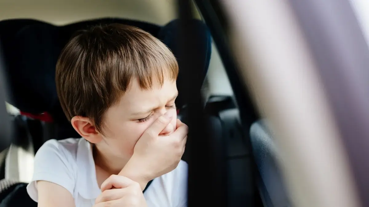 Dziecko w samochodzie zasłaniające usta
