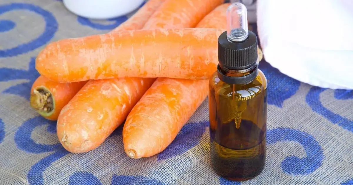 Olej marchewkowy  w buteleczce, obok świeże marchewki 