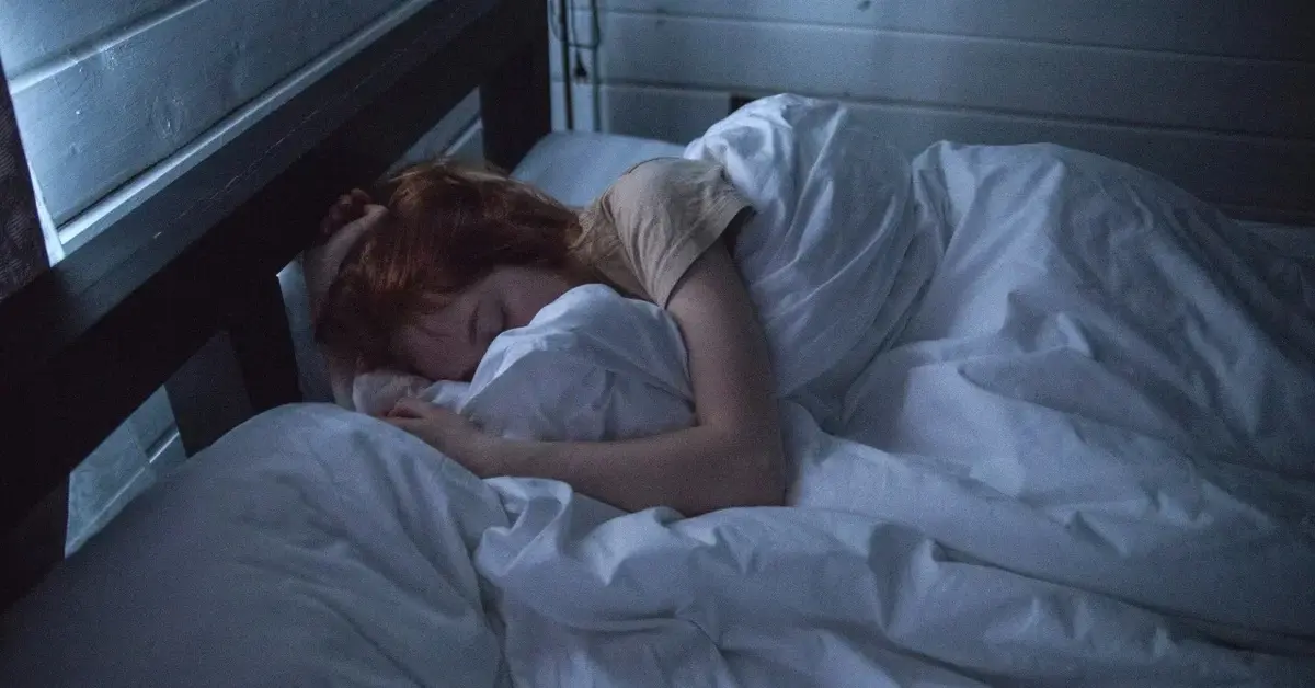 Kobieta siedząca na łóżku podpierająca głowę na rękach 