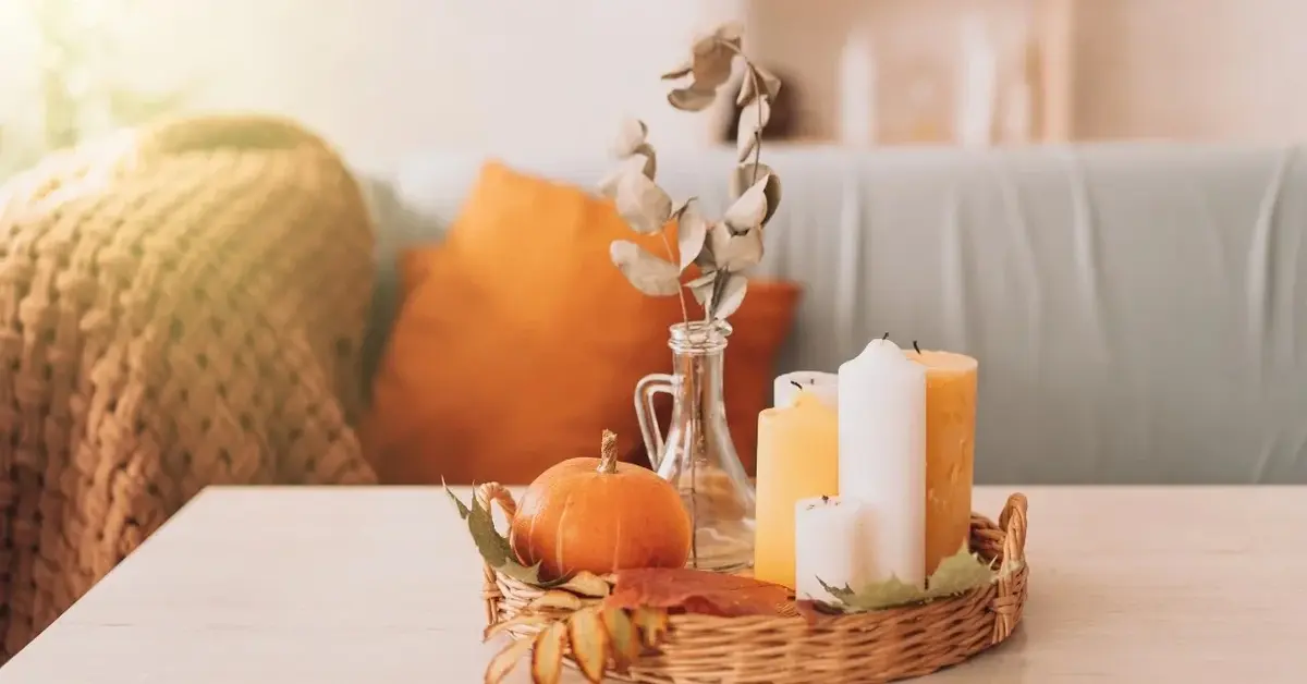 Jesienny stroik z dynią i świecami na stoliku