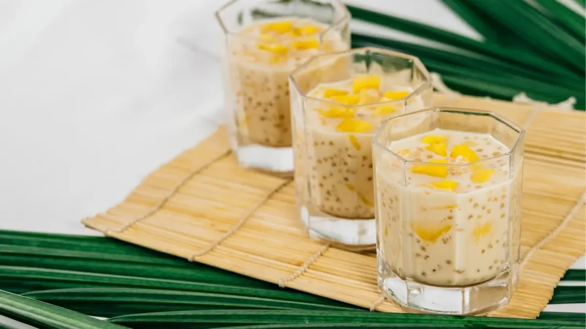 tapioka z mango w trzech szklankach na macie bambusowej i zielonych liściach palmy