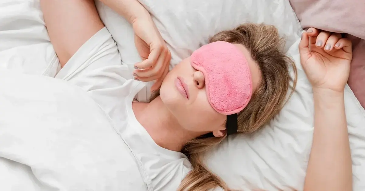 Kobieta śpiąca zdrowym snem w wygodnym łóżku z opaską na oczach