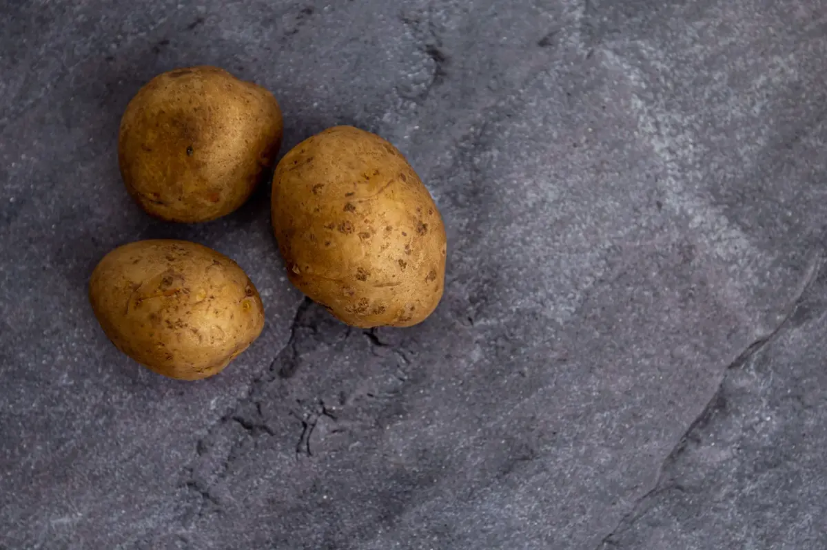 Trzy ziemniaki w skórce na szarym tle