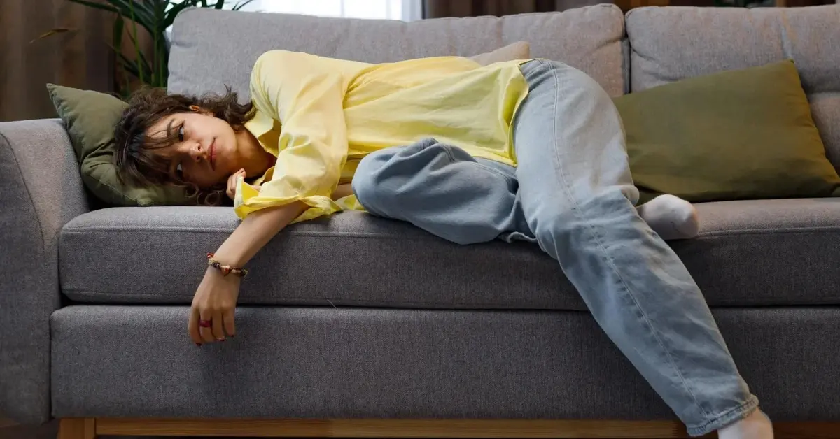 Zmęczona po pracy kobieta leży na kanapie w domu