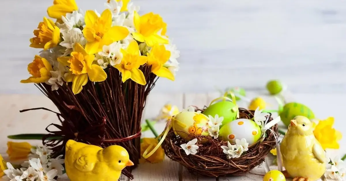 Dekoracje na wielkanocny stół: żonkile, ceramiczne kurczaczki i kolorowe jajka.