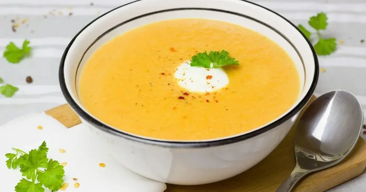 zupa marchewkowa z imbirem z białej miseczce z granatową obwódką