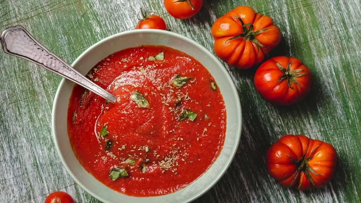 Zupa pomidorowa. Obok leżą pomidory.
