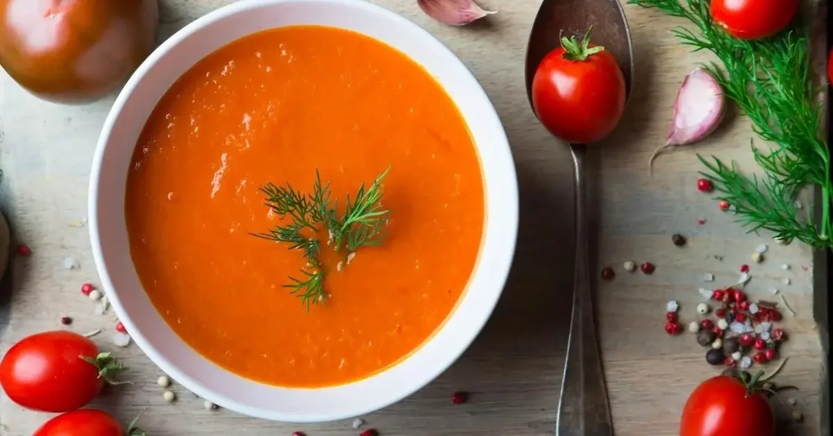 Zupa pomidorowa udekorowana koperkiem.
