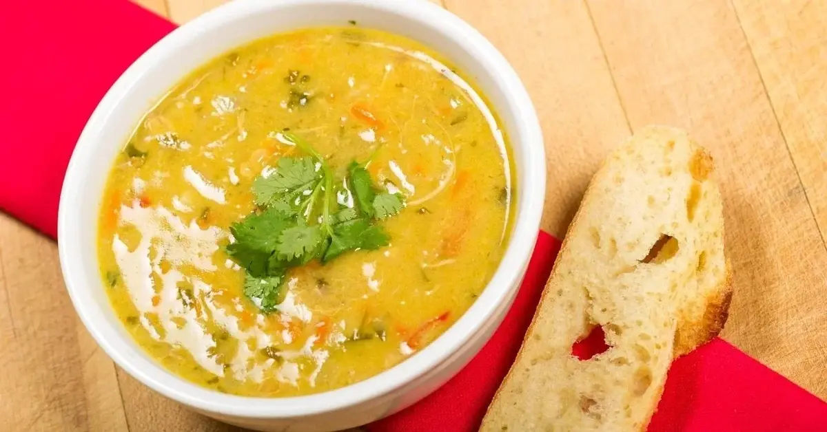 Zupa curry z kurczakiem w misce. Obok leży chleb.