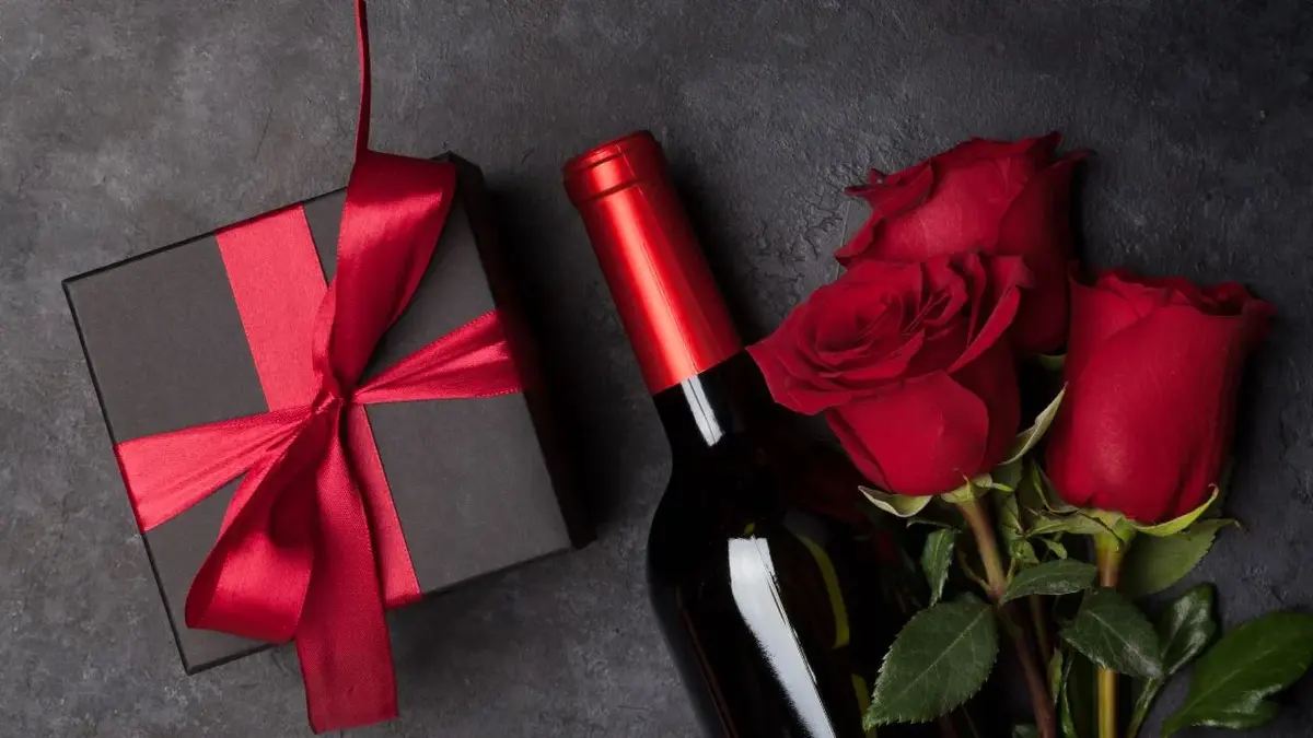 wino kwiaty i prezent na czarnym stole 