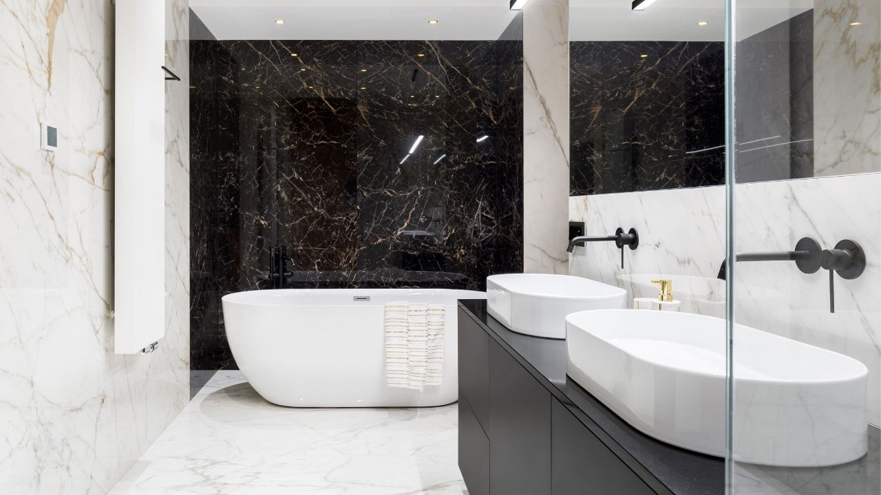 Łazienka z biało-czarnymi marmurowymi płytkami , białą wanną i dwoma białymi umywalkami